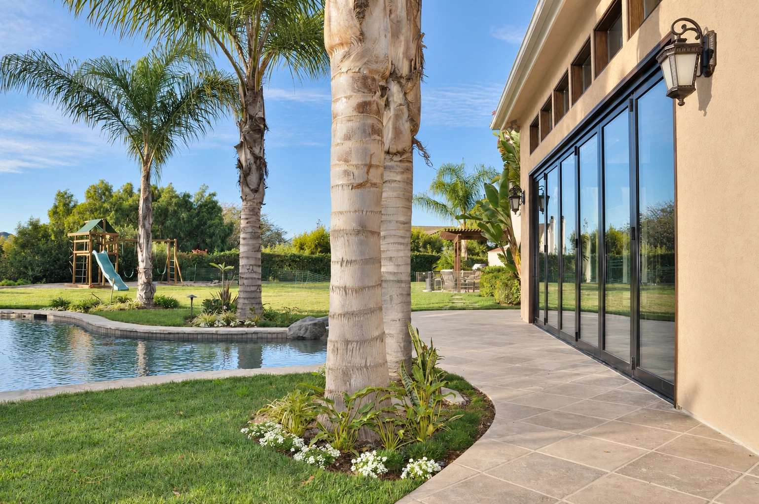 Dark framed patio doors beside a palm lined swimming pool