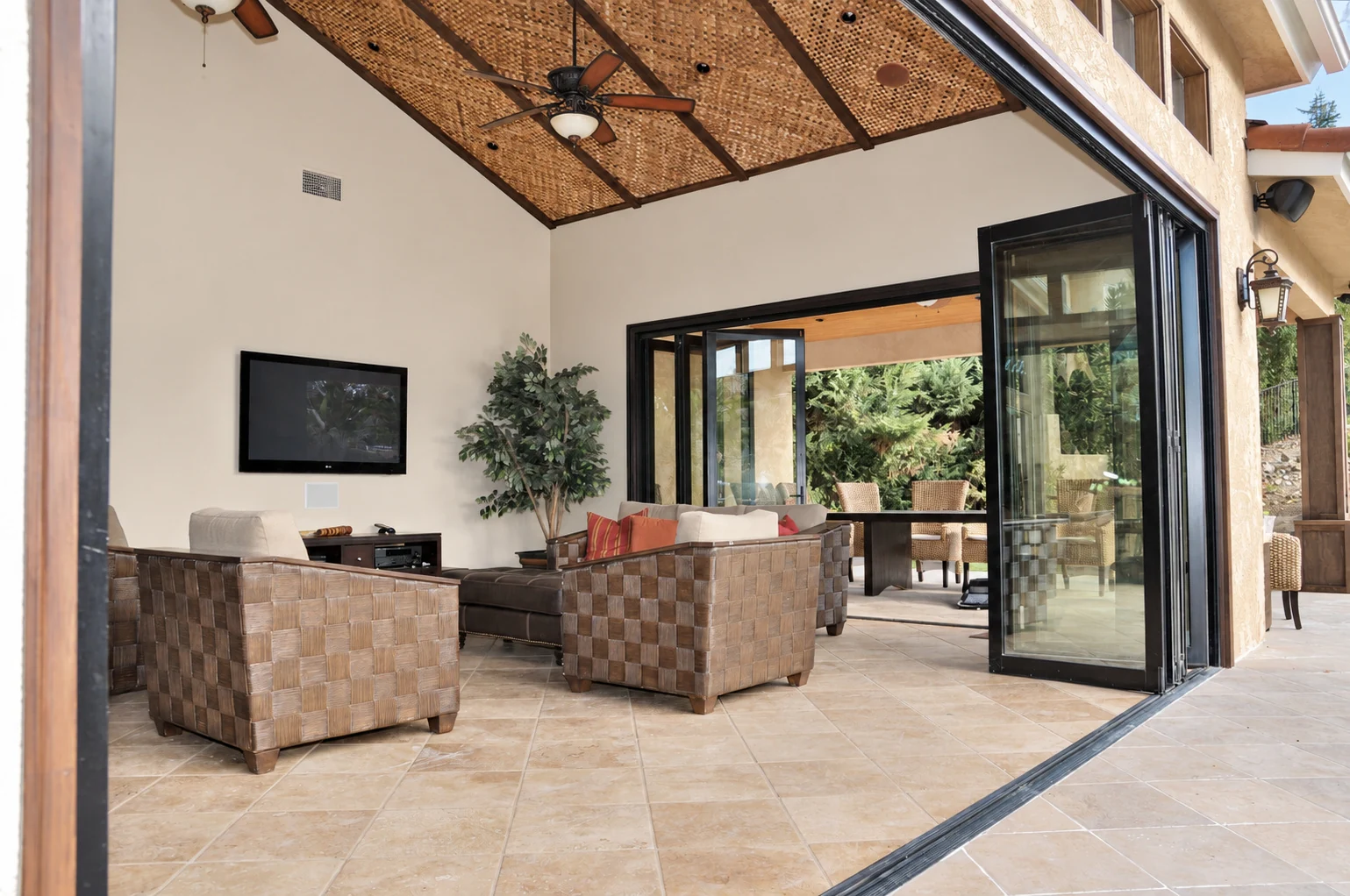 Wide folding door opening with panels stacked beside an sitting room that opens to the outdoors
