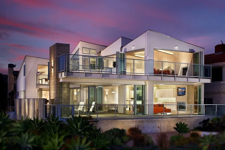 Coastal home with large glass door and window openings at dusk