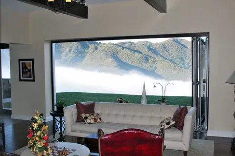 Clad folding doors framing a mountain view from a living room.