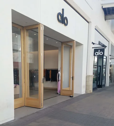 Wood folding doors at a bright retail entrance.