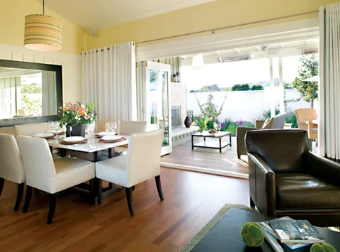 A hospitality living and dining area opening through clad glass doors.