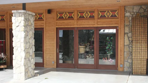 An exterior view of wood folding doors beneath a decorated timber roof.