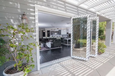 Folding panels beside a patio opening beneath a pergola.