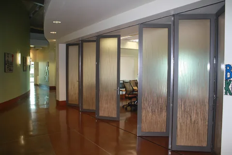 Aluminum folding panels open beside an airport interior.