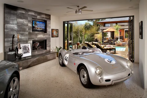 A garage lounge with folding doors open toward an outdoor pool.