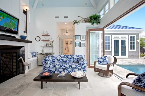 White clad folding doors connecting a living room with a covered patio.