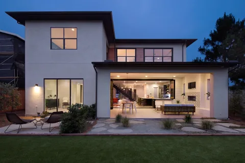 An exterior evening view of a home with a door-and-window combination.