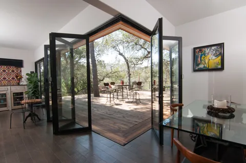 Partly folded aluminum corner doors opening a dining room to the deck.