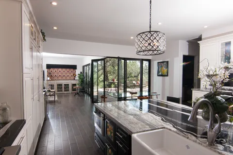Kitchen view of aluminum corner doors partly folded toward the deck.