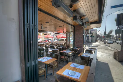 Open aluminum window panels beside restaurant dining tables.