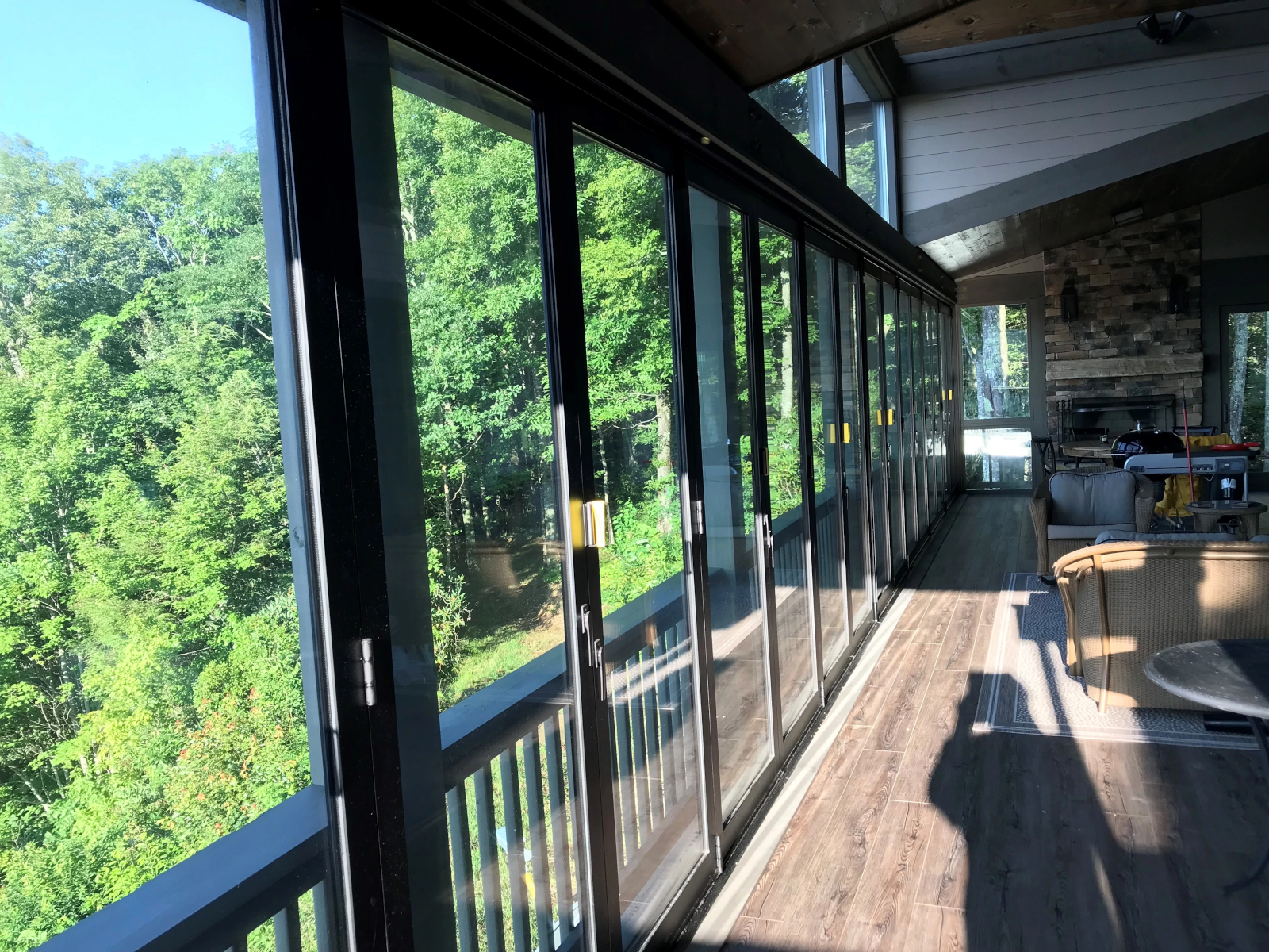 Large residential window wall creating indoor-outdoor living in forest setting.
